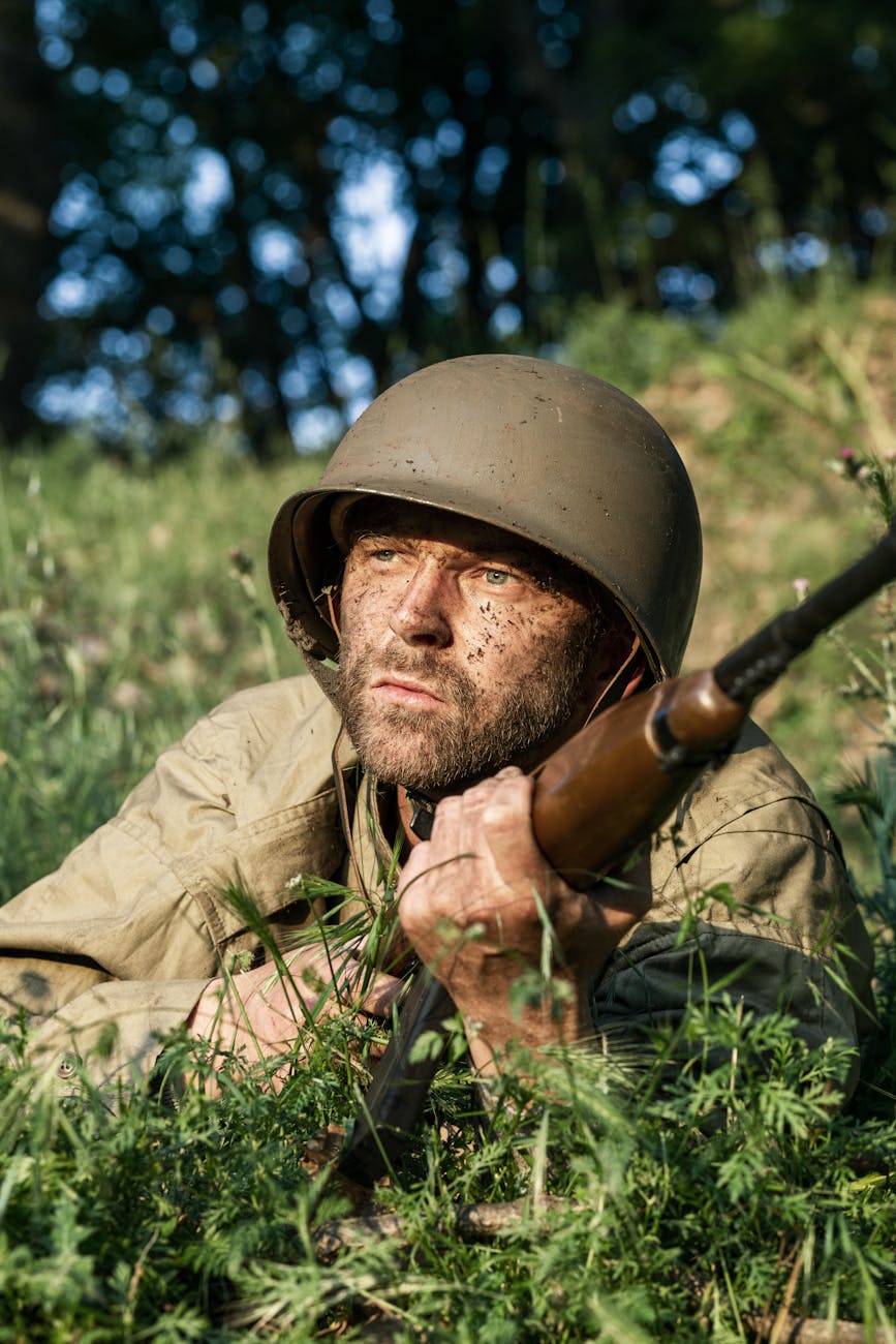 A close-up shot of a weary-looking warrior on a battlefield with a gun in hands. 