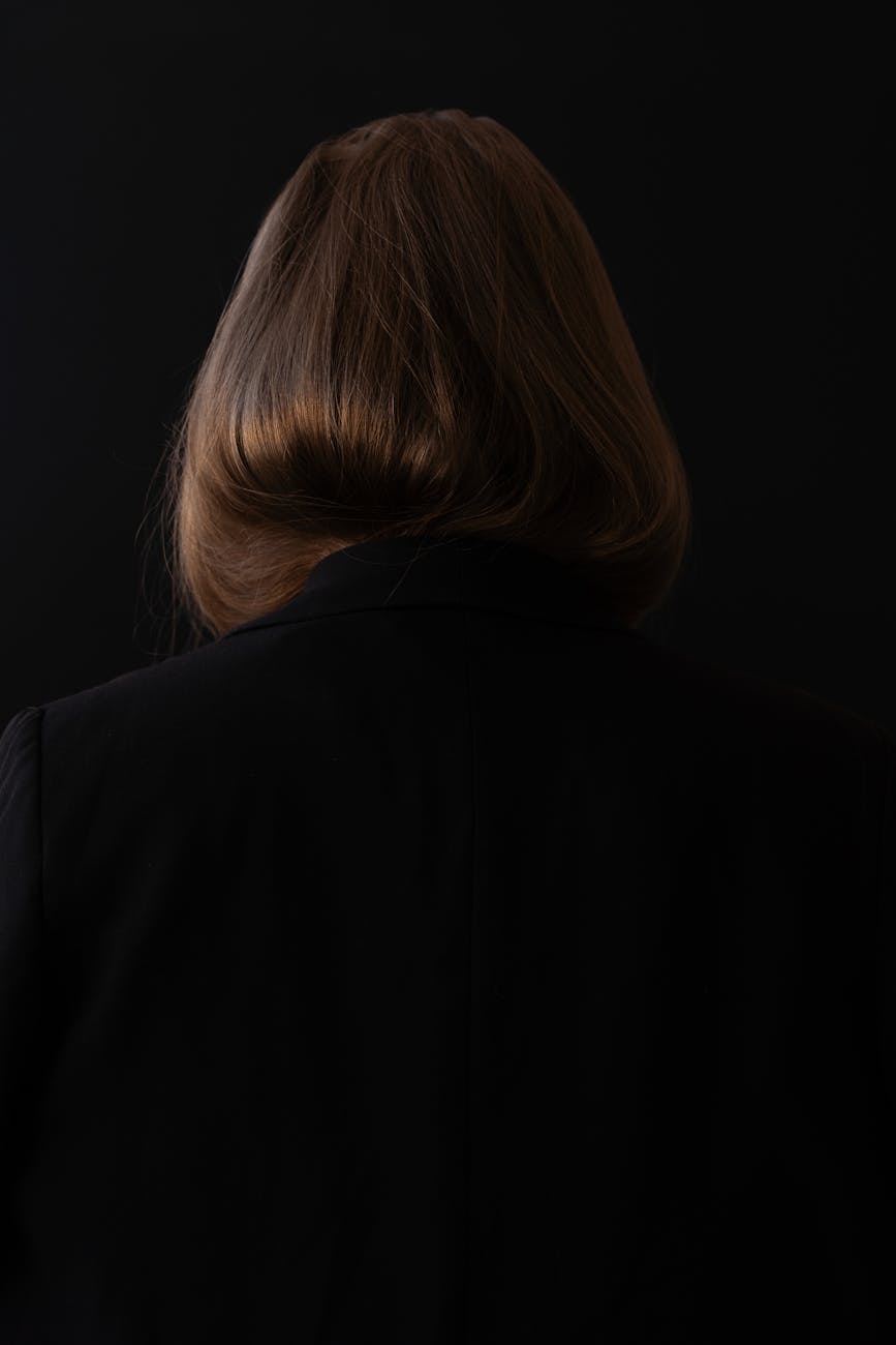 A photograph of a lady with short hair from backside. She wears a blazer. 