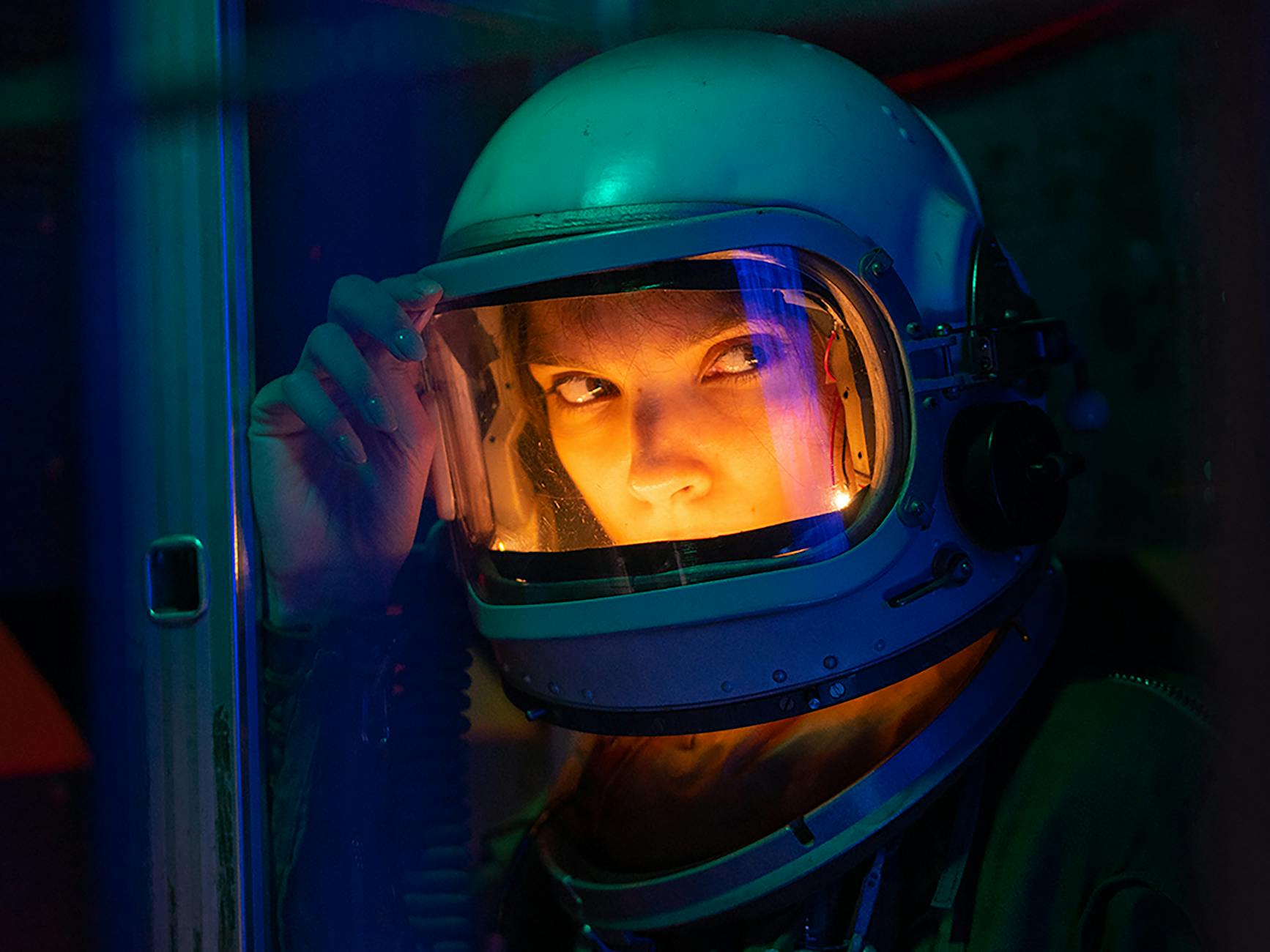 A close-up photograph of girl in spacesuit in a spcaeship. 